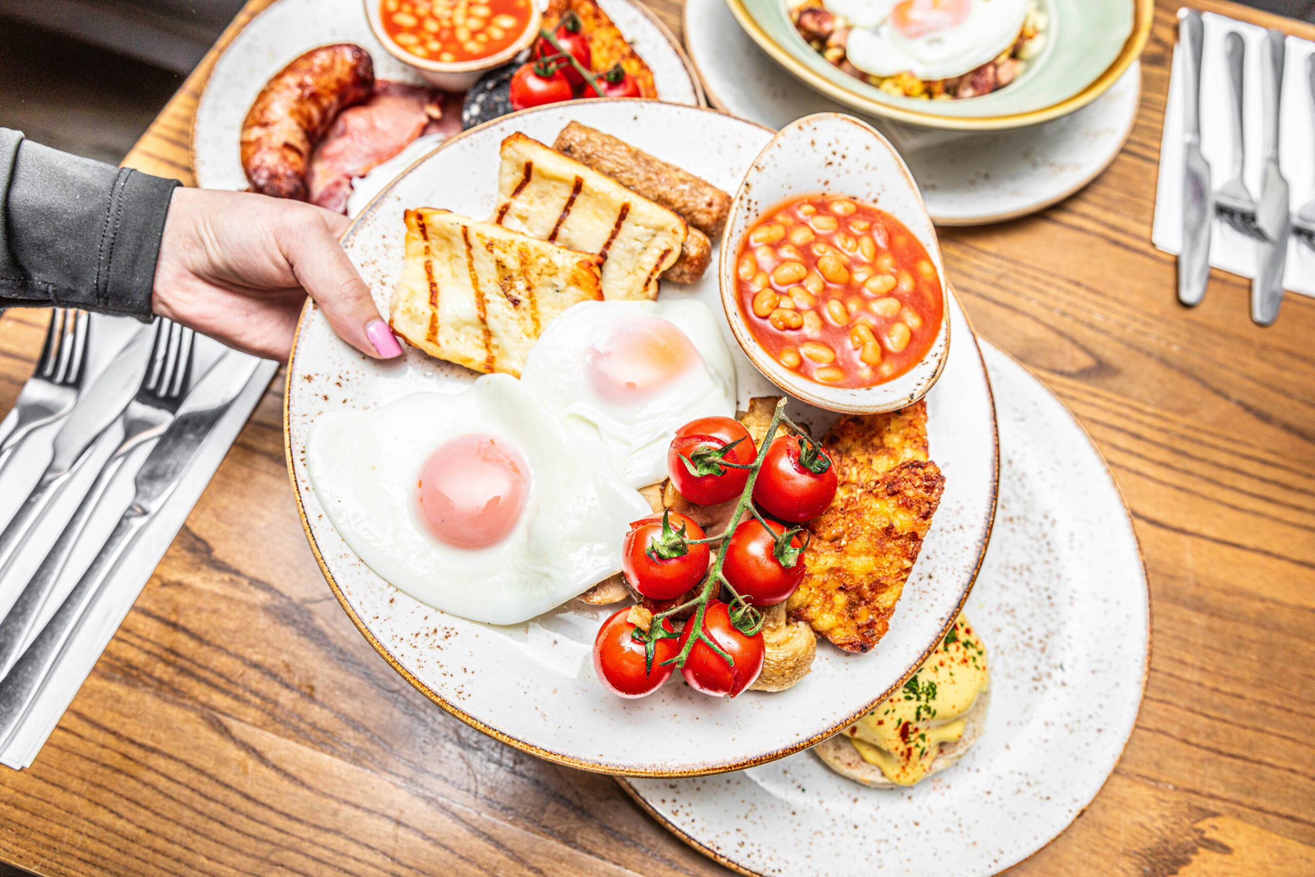 a person holding a plate of food on a table