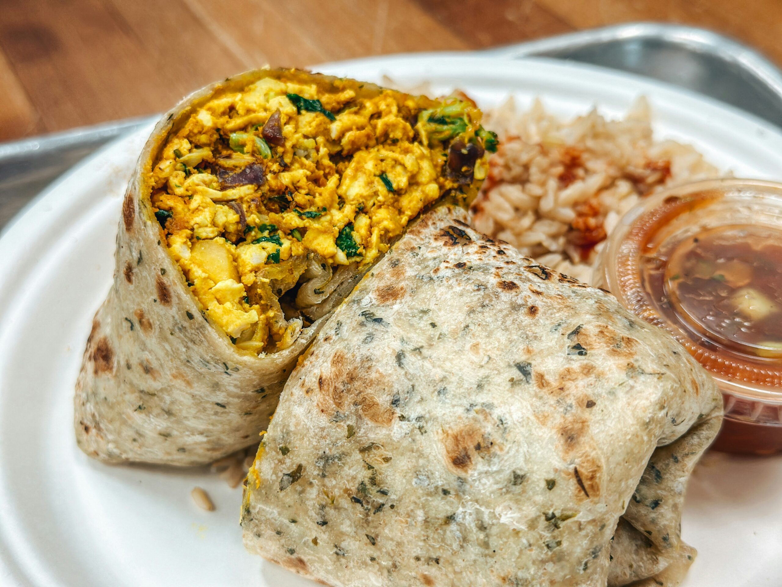 a white plate topped with a burrito and rice