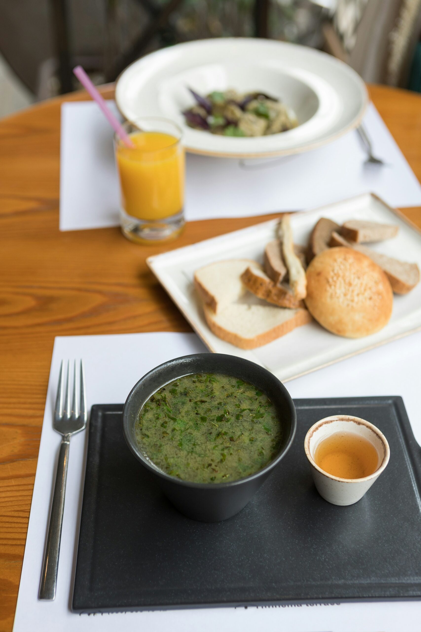 green soup on white ceramic bowl beside stainless steel fork and bread knife